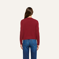 A person seen from behind, wearing a cherry red Malone Cashmere Cardigan and blue jeans.