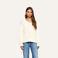 A woman wearing the Paxton Oversized Pullover in ivory and blue jeans stands facing forward against a plain, light background.