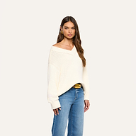 Woman with long brown hair wearing the Paxton Oversized Pullover in ivory cotton and blue jeans, posing against a plain light background.