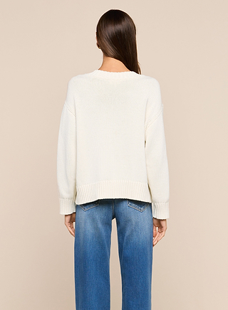 A person stands with their back to the camera, wearing the Paxton Oversized Pullover and blue jeans against a plain beige background.