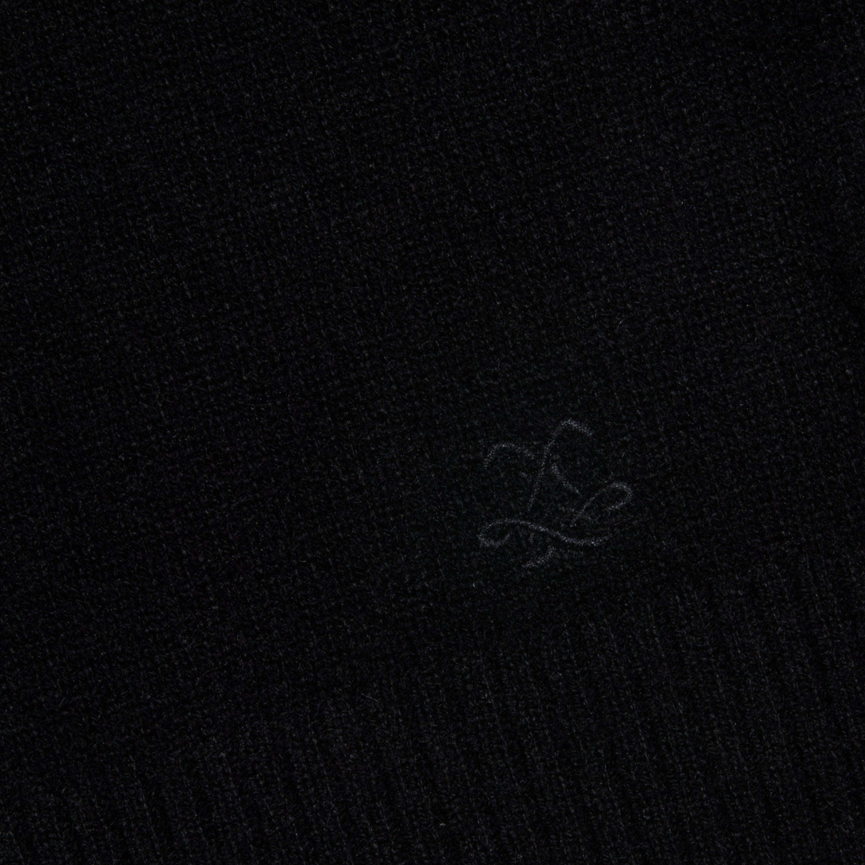 A close-up of the Filou Cashmere Tank in black, showcasing its textured fabric and a subtle embroidered design with flowing, intersecting lines near the center—an ideal detail for luxury layering or building your sweater capsule.
