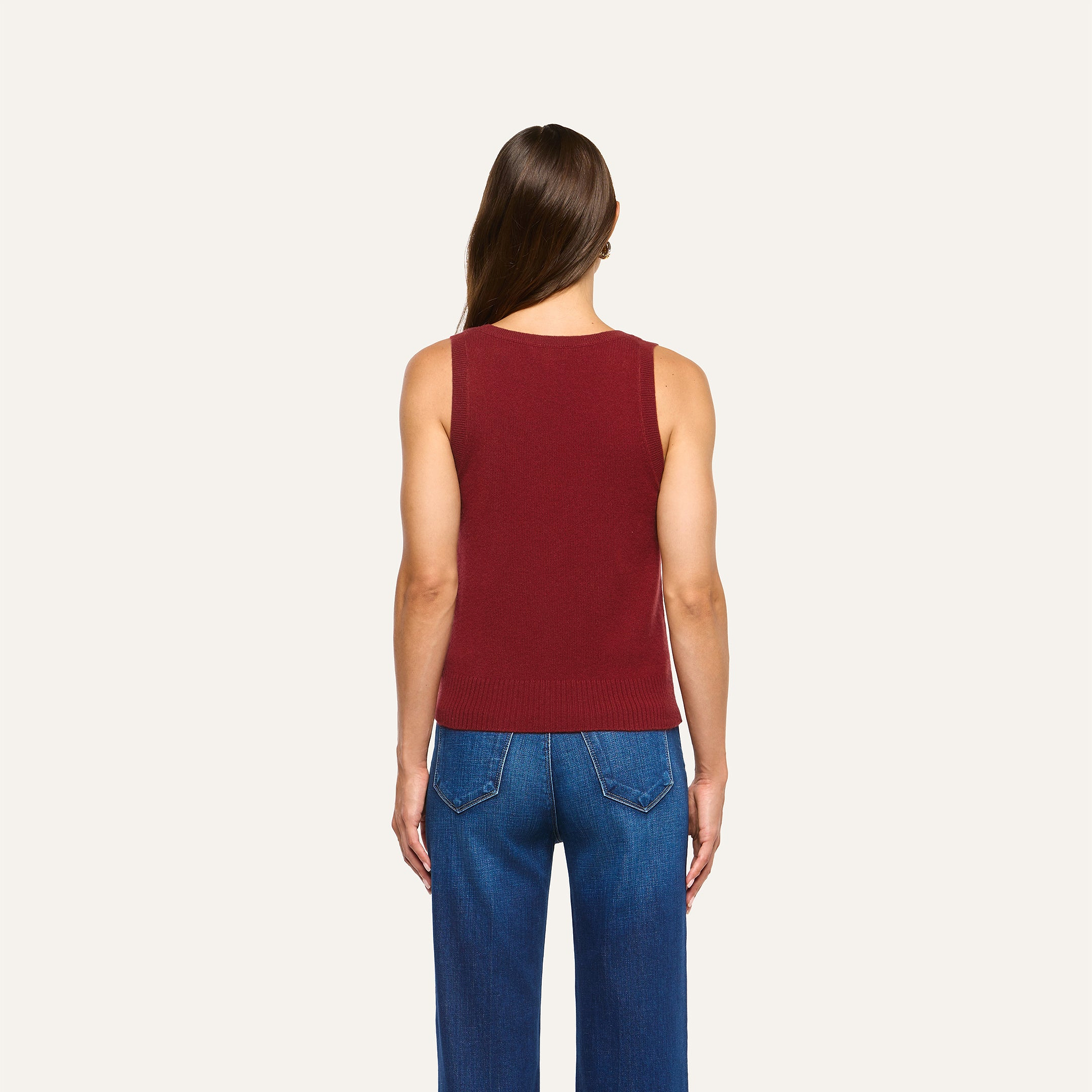 A person seen from behind wearing a maroon Filou Cashmere Tank tucked into blue jeans.