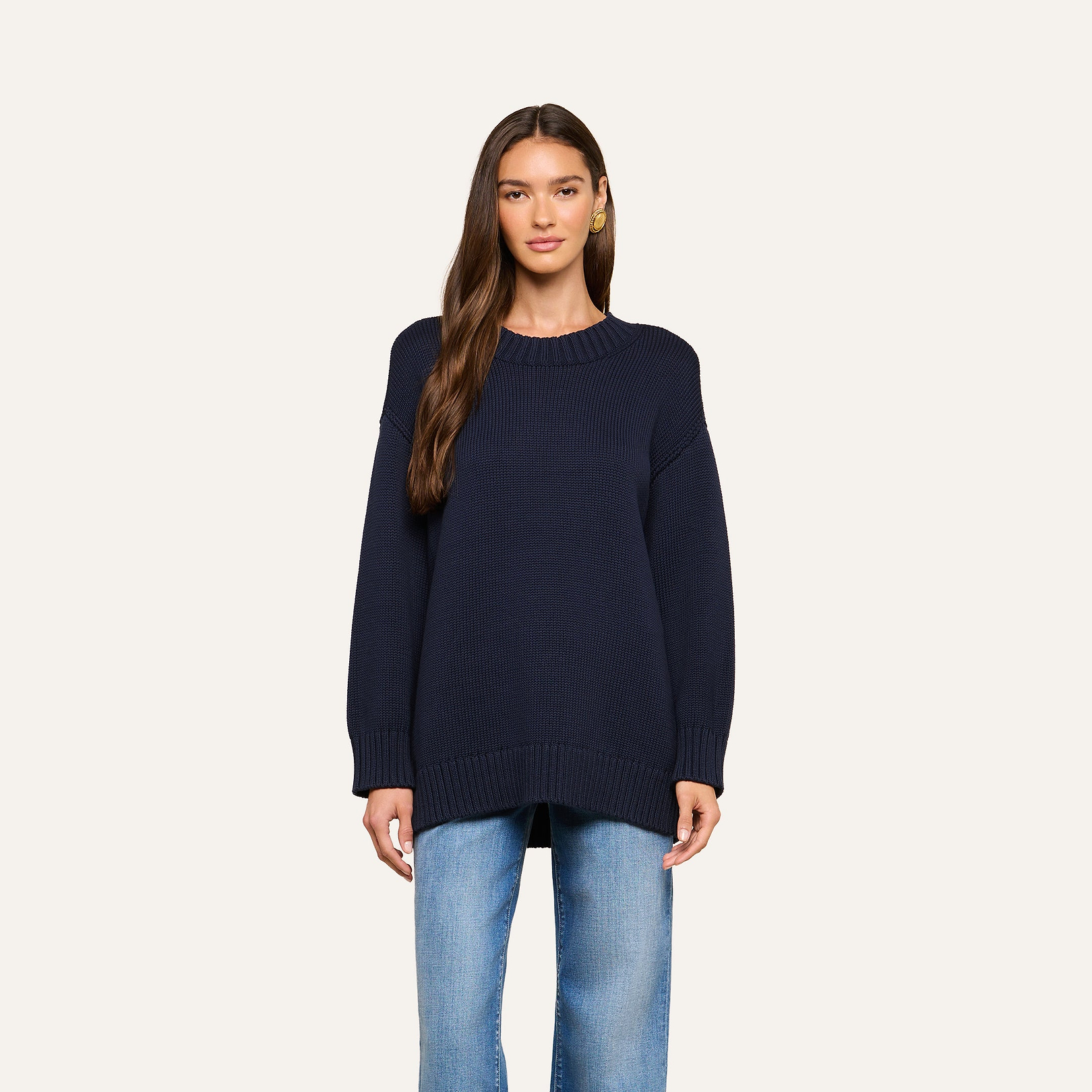 A person wearing the Loden Tunic Pullover in navy blue, styled with light blue jeans, stands facing forward against a plain light background.