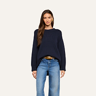 A woman is wearing the Loden Tunic Pullover in navy blue with blue jeans, standing and facing forward with a neutral expression against a plain light background.
