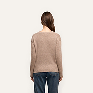 Back view of a person wearing a beige, relaxed fit Laine Cashmere Pullover and blue jeans.