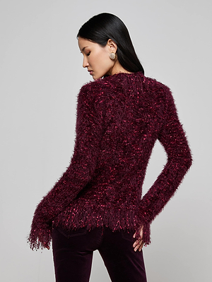 A woman with long dark hair models the L'AGENCE Azure Fringe Cardigan Blazer, posing with her back to the camera and head turned to the side against a plain light background.