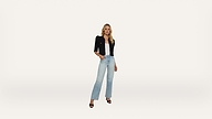 A woman stands against a plain white background, wearing a black jacket, white top, light blue high-waisted jeans, and black open-toe heels.