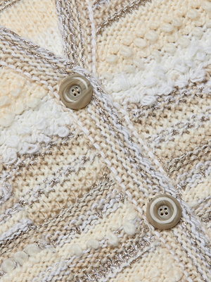 Close-up of the Harriet Cardigan’s wool-blend knit fabric in cream and beige with silver threads and two marbled buttons—perfect for a cozy look.