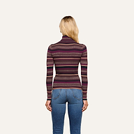 A person with long blonde hair, wearing the Olene Striped Turtleneck—a ribbed knit sweater in shades of purple—paired with blue jeans, stands facing away from the camera against a plain background for an effortlessly stylish fall look.