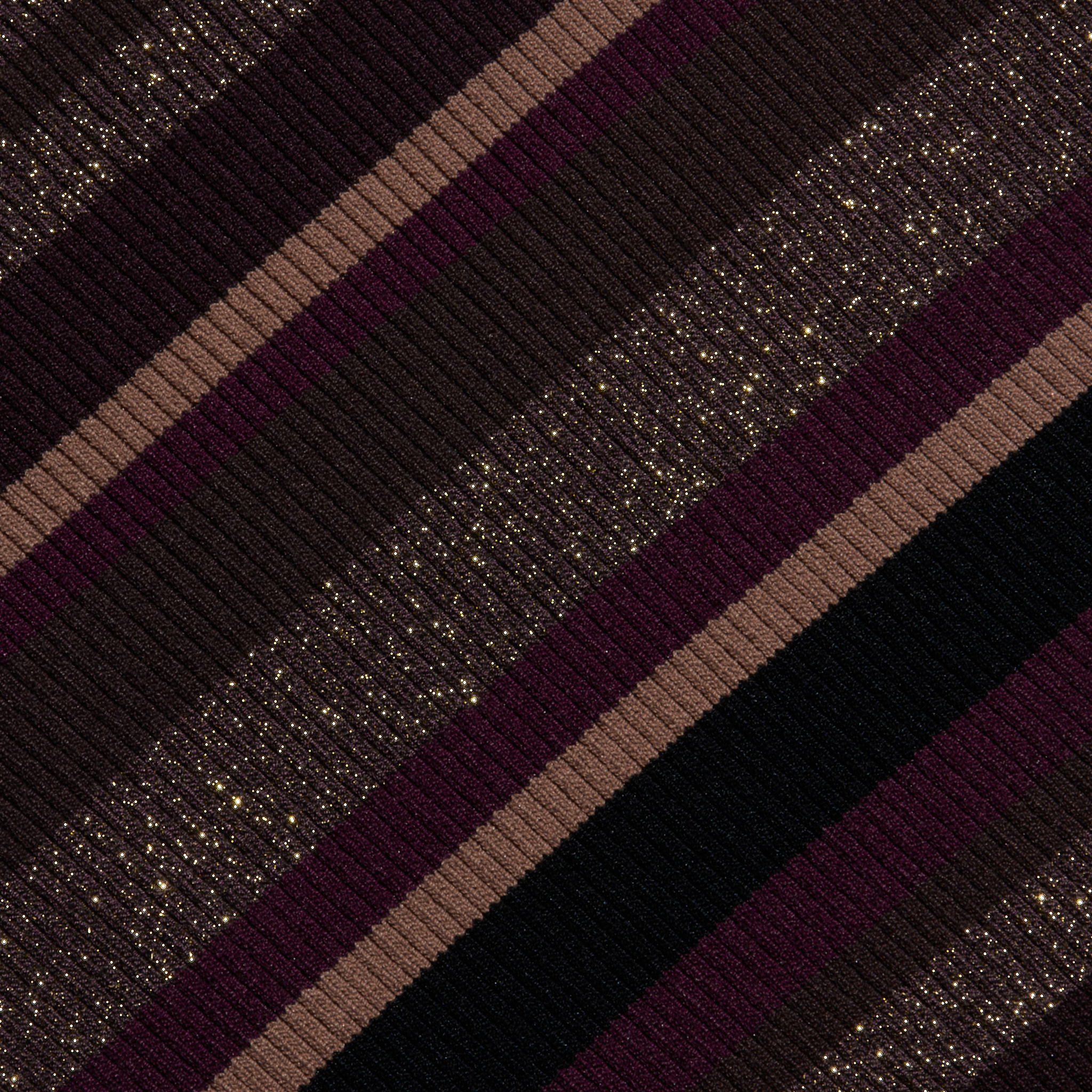 The Olene Striped Turtleneck features diagonal stripes in shades of burgundy, brown, and black with a ribbed knit texture and gold glitter specks throughout the fabric, making it a stylish choice for fall fashion.