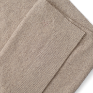 Palais Cashmere Scarf in tan, featuring a folded pebbled texture, a ribbed hem, and a small embroidered emblem.