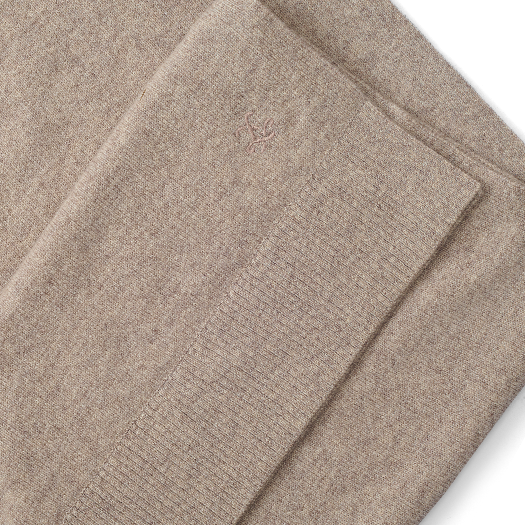 Palais Cashmere Scarf in tan, featuring a folded pebbled texture, a ribbed hem, and a small embroidered emblem.