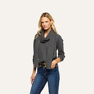 A woman wearing a charcoal grey Palais Cashmere Scarf draped over a matching long-sleeve sweater and blue jeans.