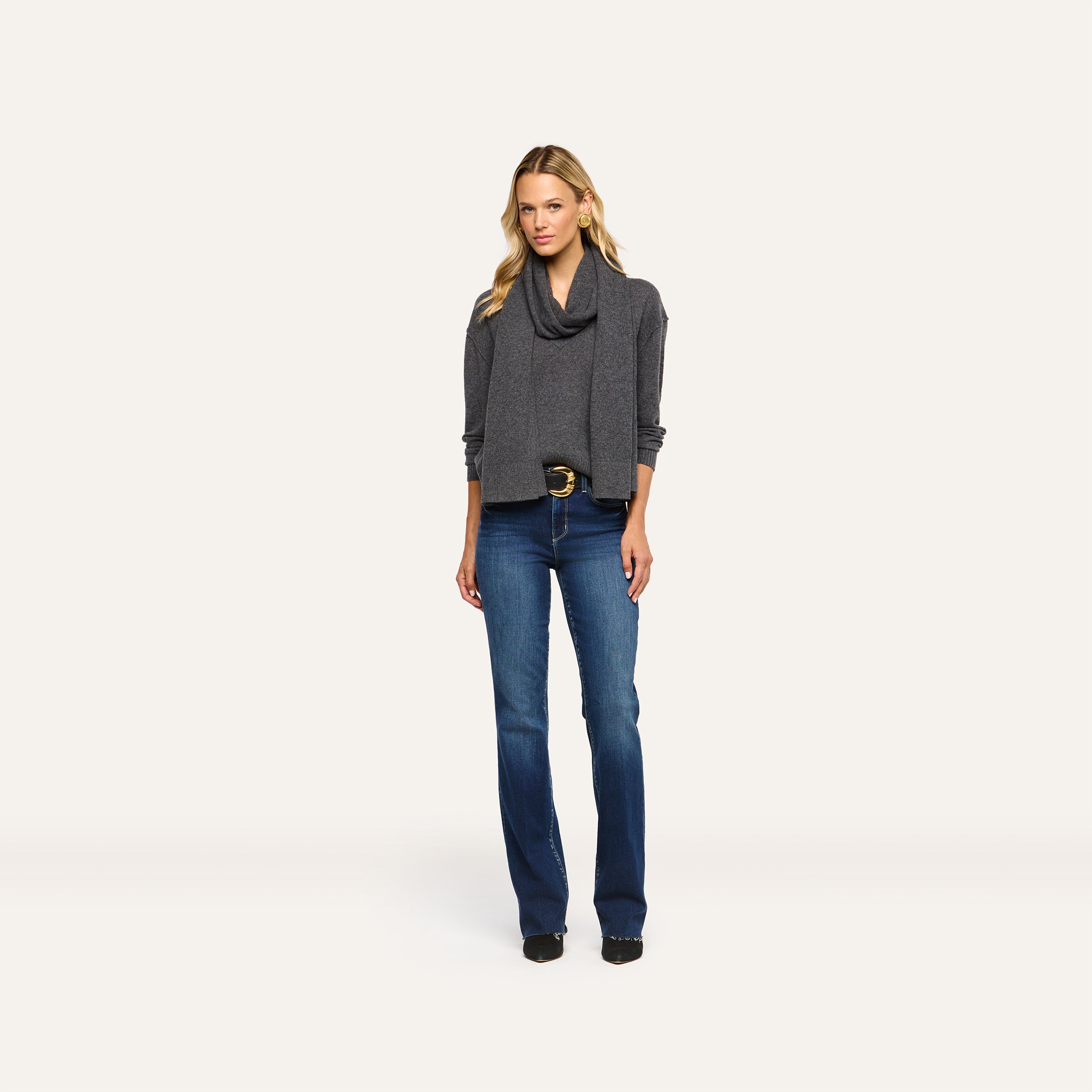 A woman wearing a charcoal grey Palais Cashmere scarf over a matching sweater and blue jeans.