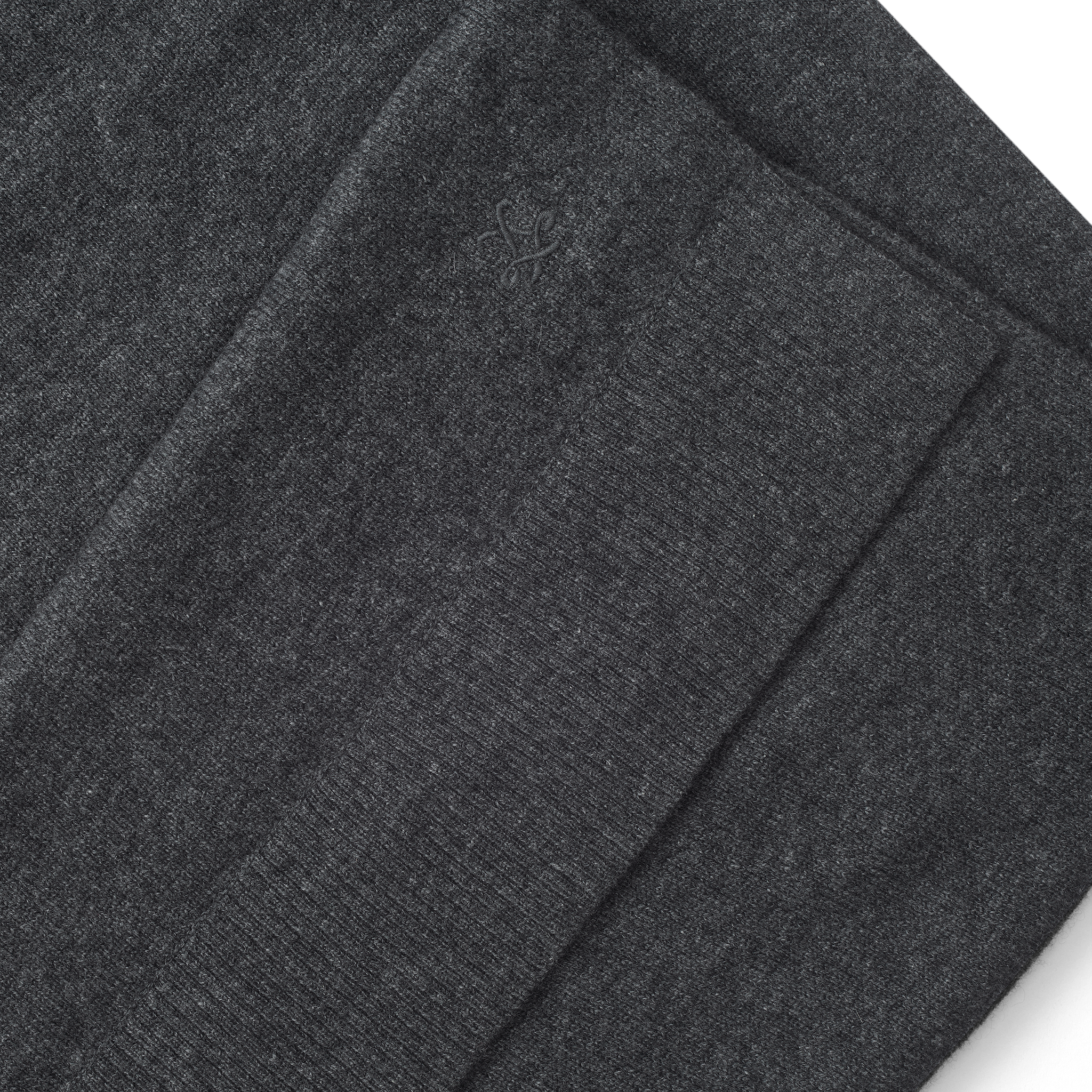 Folded charcoal grey Palais Cashmere Scarf with a small embroidered emblem.