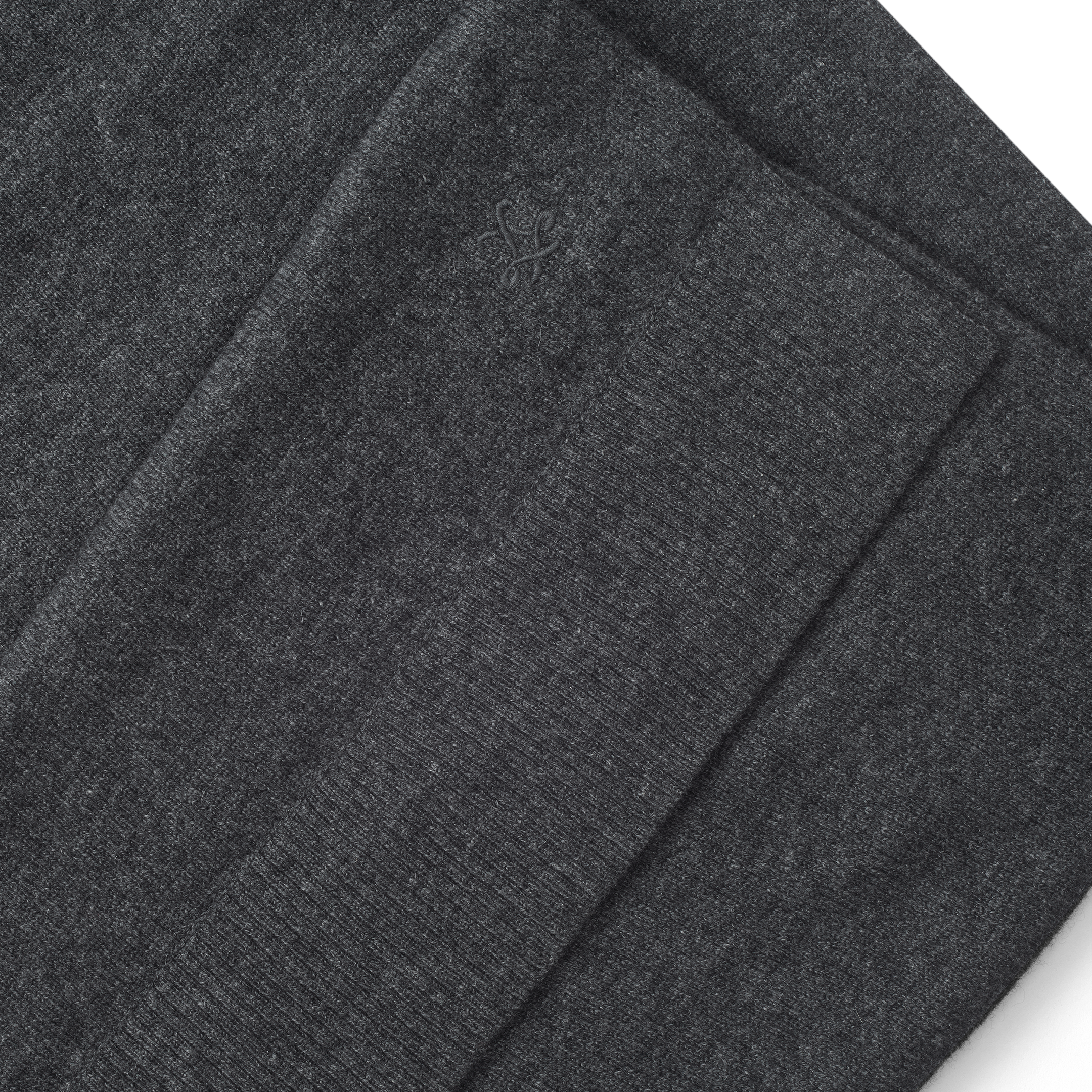 Folded charcoal grey Palais Cashmere Scarf with a small embroidered emblem.