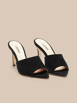 The Lolita Suede Open-Toe Mule, featuring black suede and beige insoles with LAGENCE branding, is displayed on a neutral beige background.