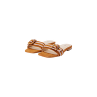 The Aurelie Buckle Sandal is a pair of tan suede slide sandals with a low heel, showcasing white stitching and a bamboo buckle detail on the strap, displayed against a white background.