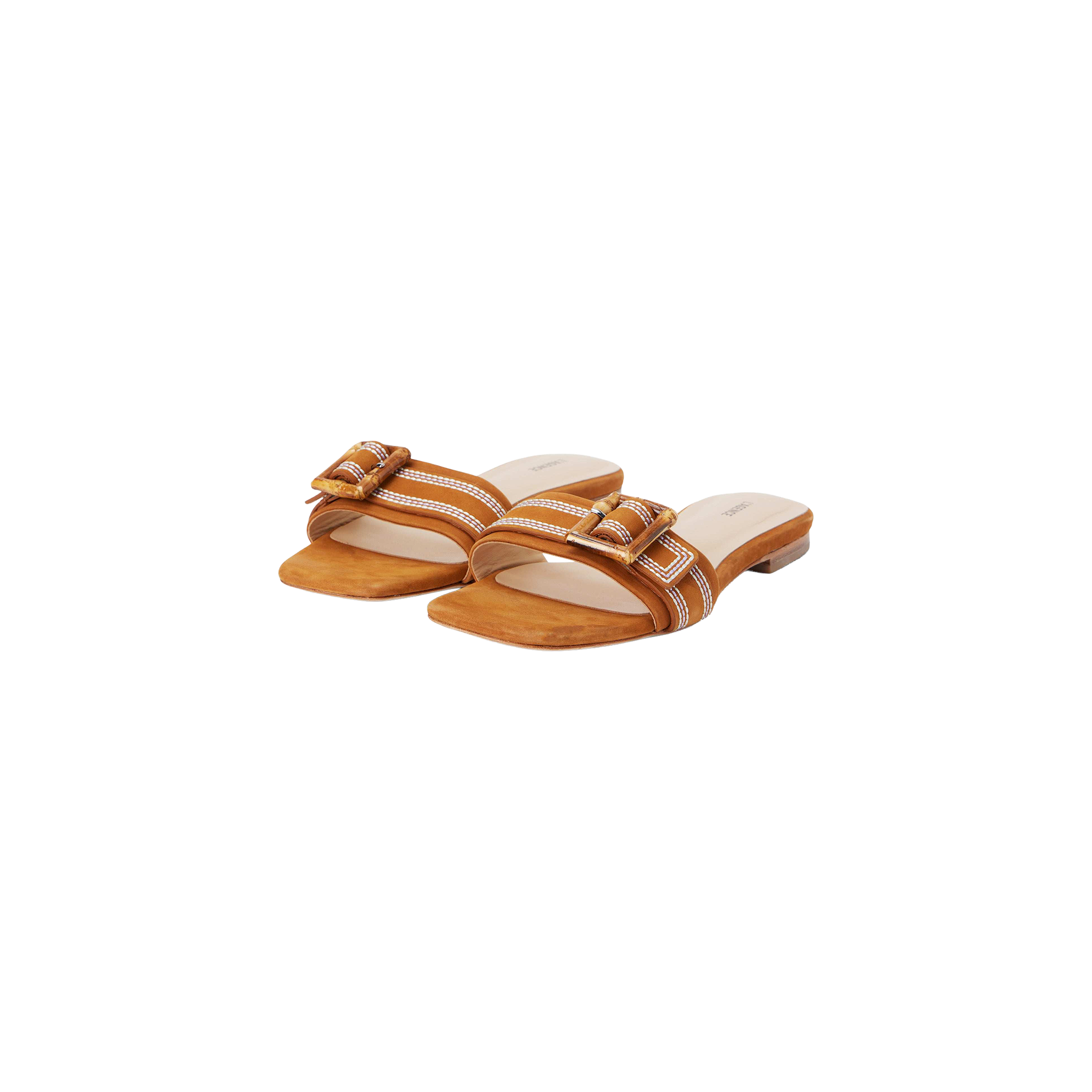 The Aurelie Buckle Sandal is a pair of tan suede slide sandals with a low heel, showcasing white stitching and a bamboo buckle detail on the strap, displayed against a white background.