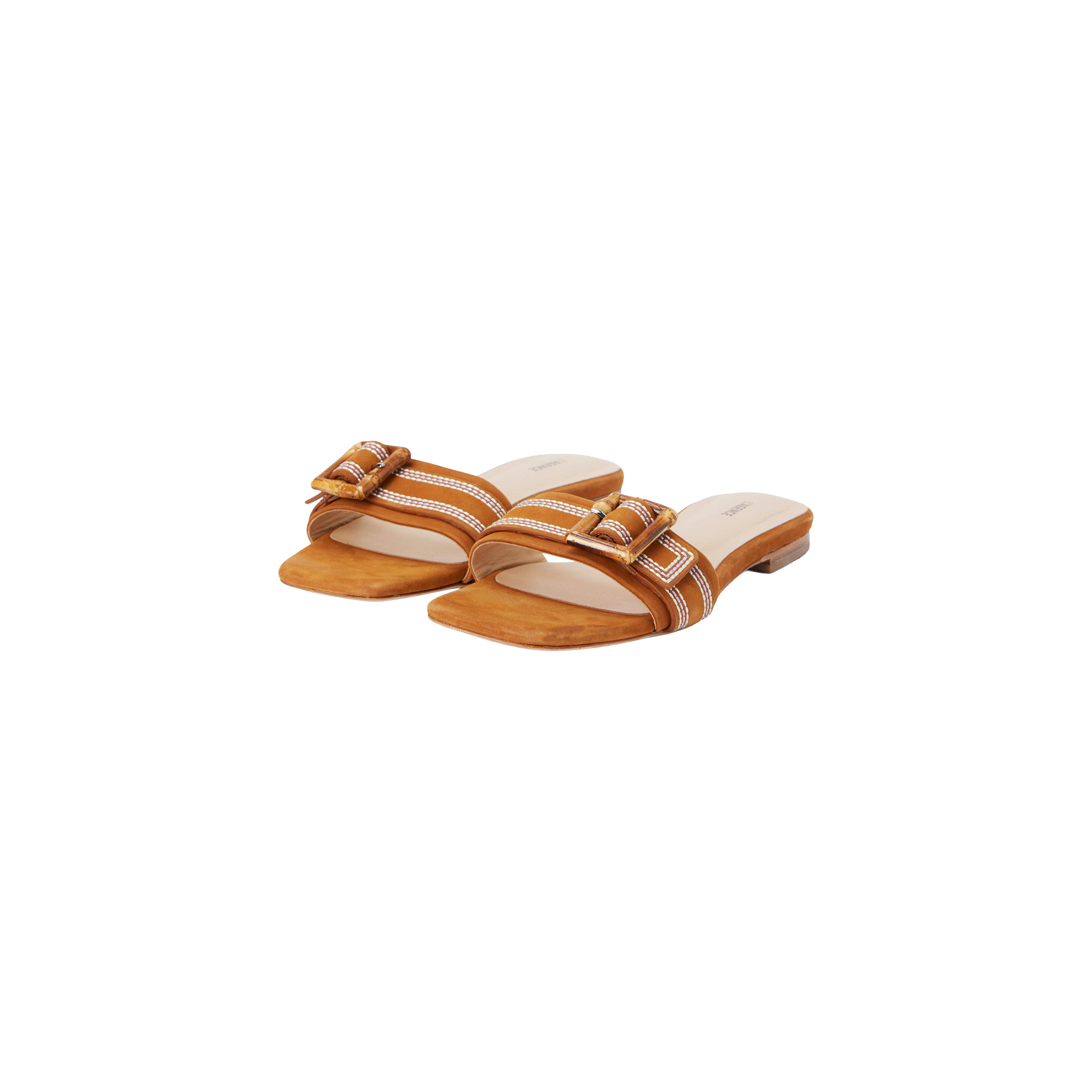 The Aurelie Buckle Sandal is a pair of tan suede slide sandals with a low heel, showcasing white stitching and a bamboo buckle detail on the strap, displayed against a white background.