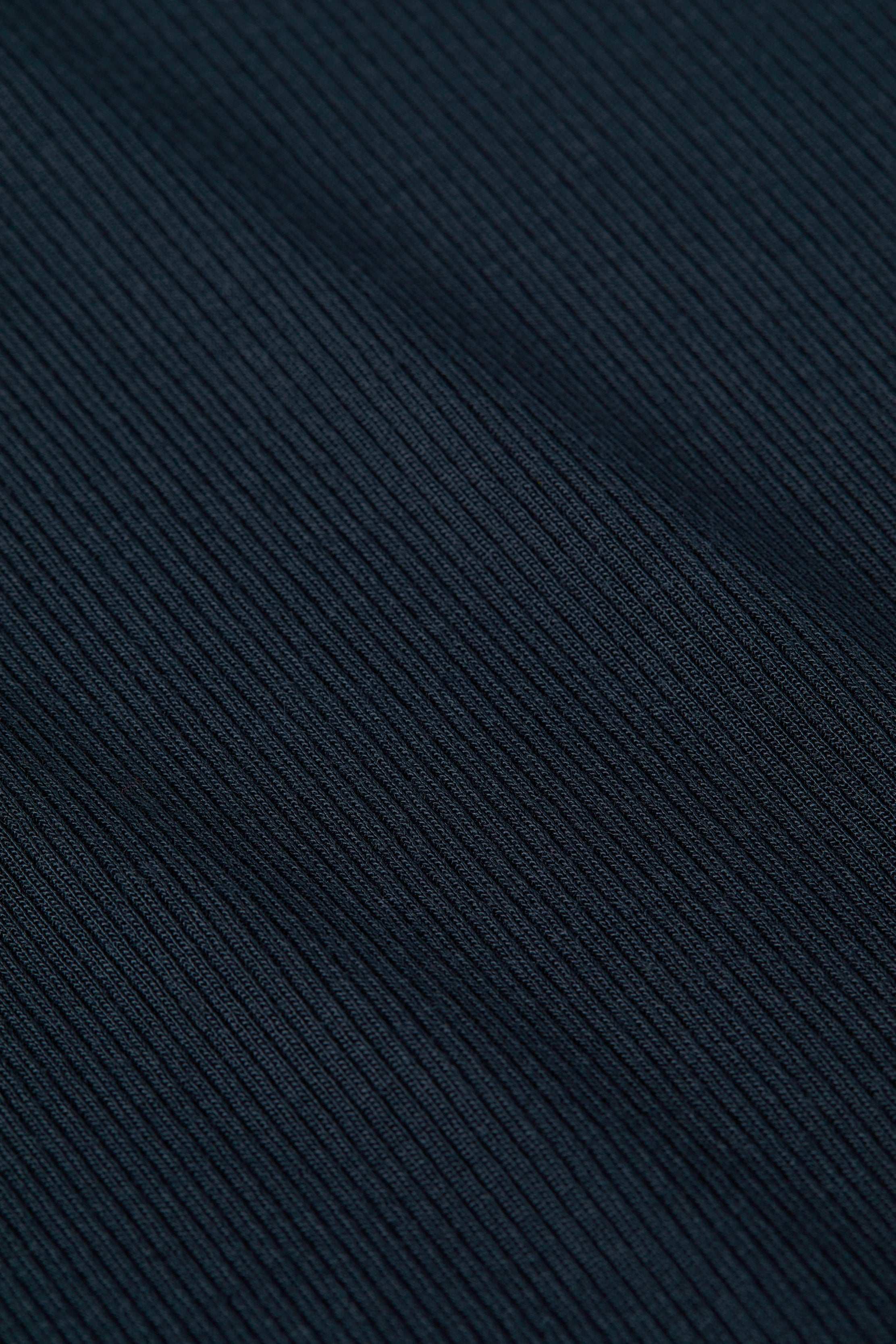 Close-up of the Ressi Micro-Rib Tee’s dark, ribbed microfiber fabric with diagonal textured lines, featuring fine, detailed stitching and a soft material appearance.