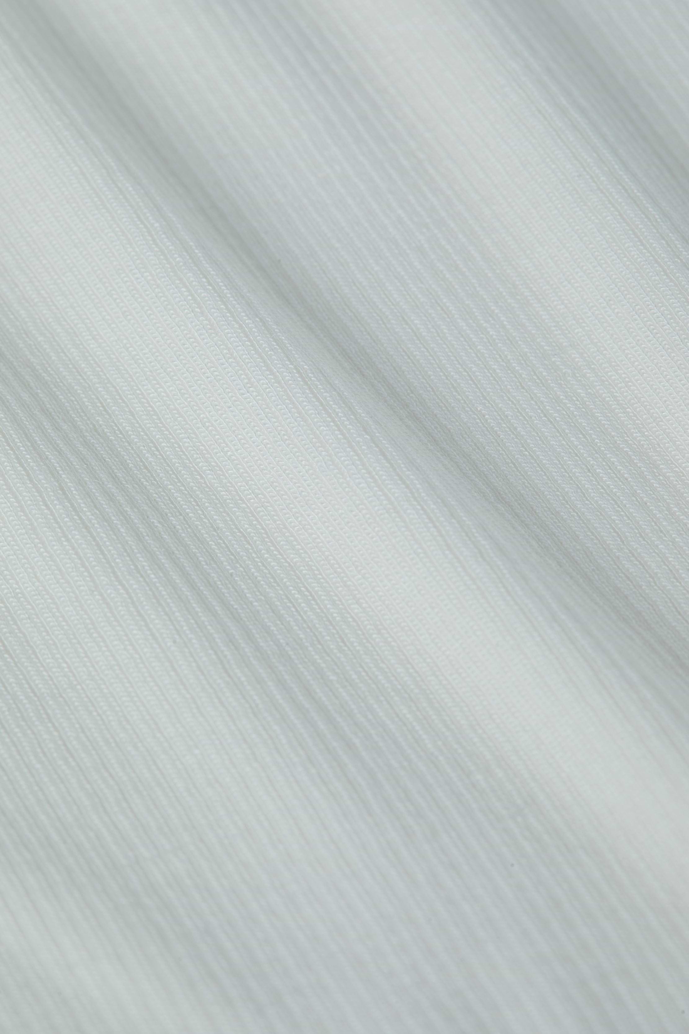 Close-up of the Ressi Micro-Rib Tee in white, showcasing its fine vertical ribbed texture and soft folds that create subtle shadows and highlights.