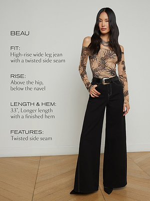 A woman stands indoors wearing high-rise wide leg black jeans and a fitted, long-sleeve, off-shoulder printed top. Text beside her describes the jeans’ fit, rise, length, hem, and twisted side seam feature.