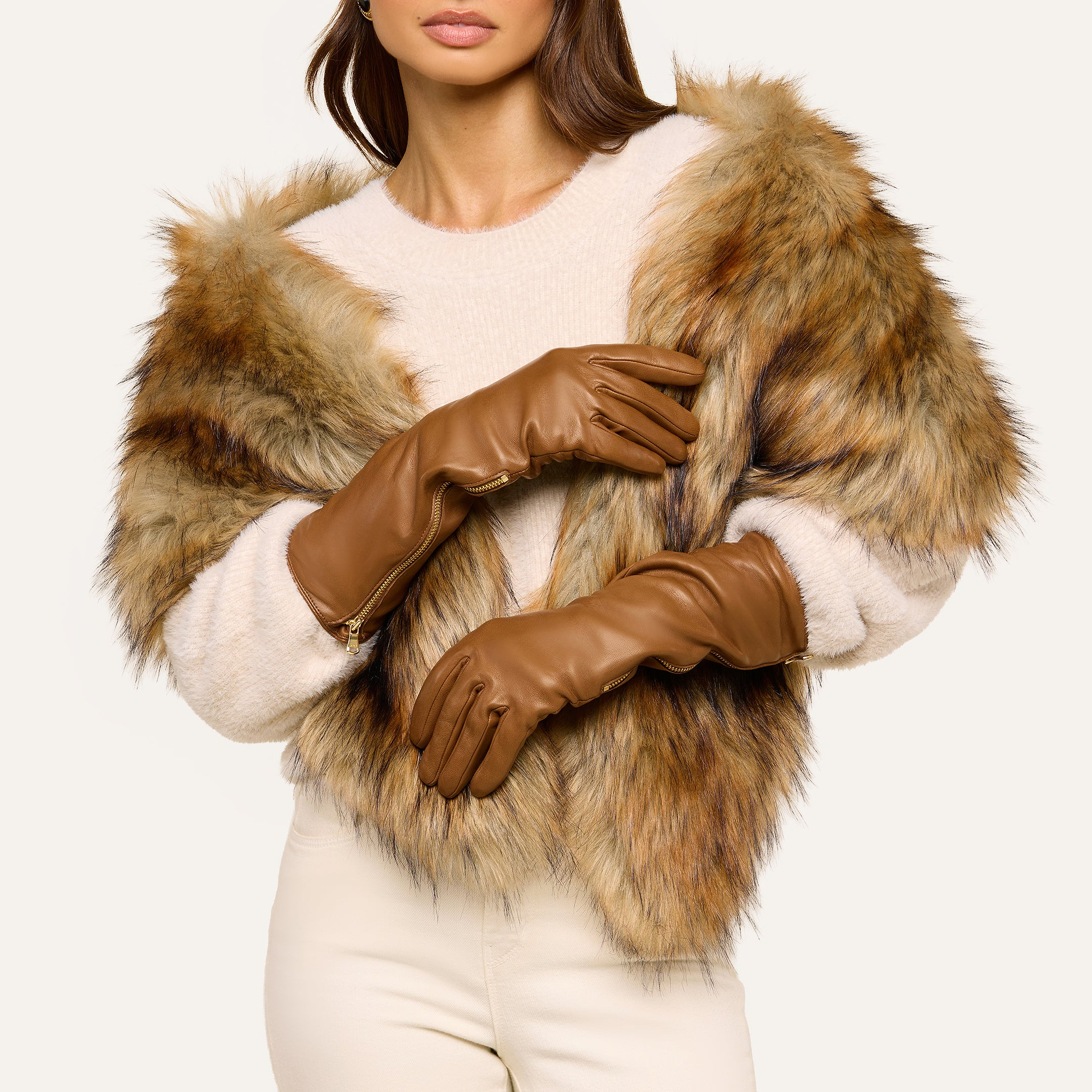 A woman wearing the Carmen Gloves poses with her arms crossed in front of her torso, styled in a faux fur jacket, cream sweater, and beige pants against a light background.