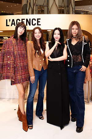 Four women stand together in a stylish boutique, each wearing fashionable outfits including blazers, jeans, dresses, and boots. The store sign LAGENCE is displayed behind them.