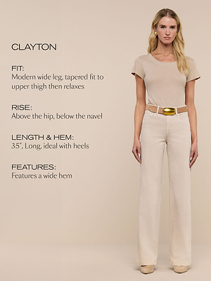 A woman stands against a beige background wearing a beige t-shirt, wide-leg cream pants with a belt. Text describes the pants: modern wide leg, relaxed fit, rise above the hip, 35 length, and a wide hem.