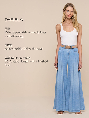 Eine Frau trägt ein weißes Tanktop und hellblaue, weit geschnittene Palazzo-Jeans mit einem hellbraunen Gürtel vor einem einfarbig beigen Hintergrund. Der Text beschreibt die Passform, die Leibhöhe, die Länge und die Saumdetails der Jeans.