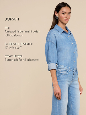Une femme porte une chemise en denim bleu clair à la coupe décontractée, avec des manches roulées et un jean bleu clair. Le texte décrit la coupe de la chemise, la longueur des manches de 19 avec un revers, et la patte de boutonnage pour les manches roulées.