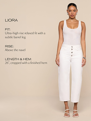 A woman stands against a beige background, wearing a white tank top and high-rise white jeans with four buttons. Text beside her describes the jeans fit, rise above the navel, and cropped 26-inch length with a finished hem.