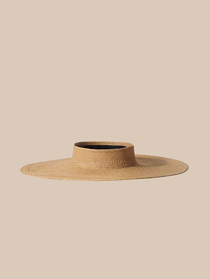 The Flor Visor is a wide-brimmed, handcrafted straw hat with a flat crown that provides stylish sun protection, shown against a plain beige background.