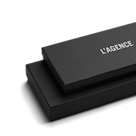 Two stacked black rectangular boxes, the top one slightly smaller and labeled LAGENCE in white text, set against a plain white background—an elegant presentation reminiscent of luxury accessories such as the Tempo Mittens.