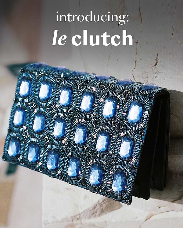 Blue beaded clutch on a marble surface with 'introducing: le clutch' text.