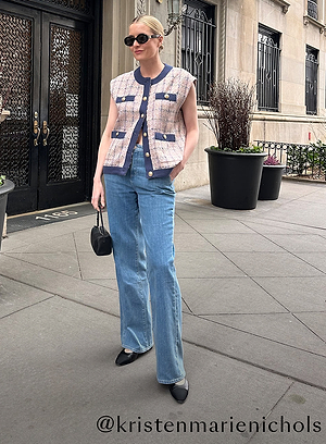 A woman stands on a city sidewalk wearing sunglasses, a sleeveless tweed vest, a black top, blue high-waisted jeans, and black shoes. She holds a small black handbag. Text @kristenmarienichols is written at the bottom.