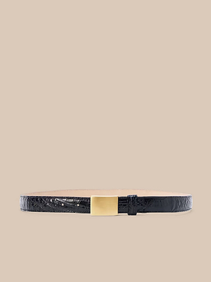 La cintura Amis, una cintura nera artigianale con motivo a coccodrillo e fibbia rettangolare in oro, è presentata su uno sfondo beige.