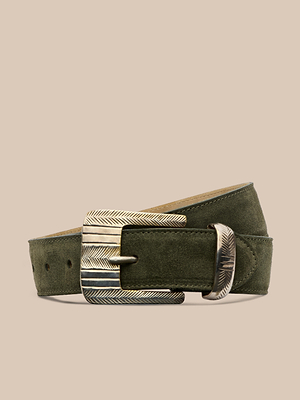 The Aya Suede Belt in olive green Italian suede features a textured, engraved metal buckle and loop. Handcrafted in LA, it is displayed against a neutral beige background.