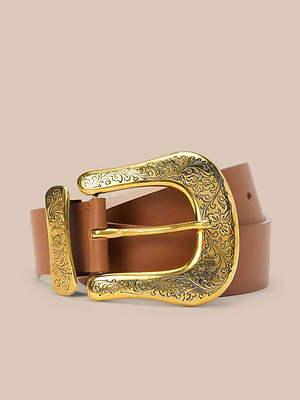 The Ximena Belt, handcrafted in LA from Italian leather, features a tan strap and an ornate gold-toned buckle with floral engravings—adding Western flair when showcased on a beige background.