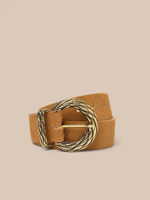 La ceinture Adelle est une pièce artisanale en daim fauve, dotée dune grande boucle ronde plaquée or en forme de corde torsadée, sur un fond beige uni.