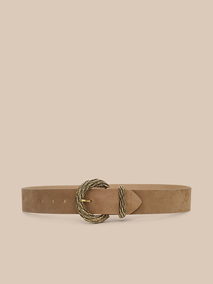 The Adelle Suede Belt is a wide, light brown Italian suede accessory with a handcrafted twisted rope-textured antique gold buckle, shown on a plain beige background.