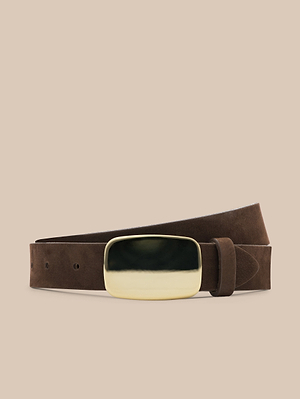 The Hennie Suede Belt, handcrafted in LA from chocolate suede, features a large rectangular gold-plated buckle and is showcased against a neutral beige background.