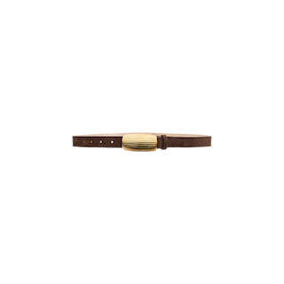 The Machado Suede Belt, handcrafted in Italy from rich brown suede, features a slim design and a textured oval-shaped gold buckle. Displayed against a plain white background, this belt embodies timeless elegance and refined style.