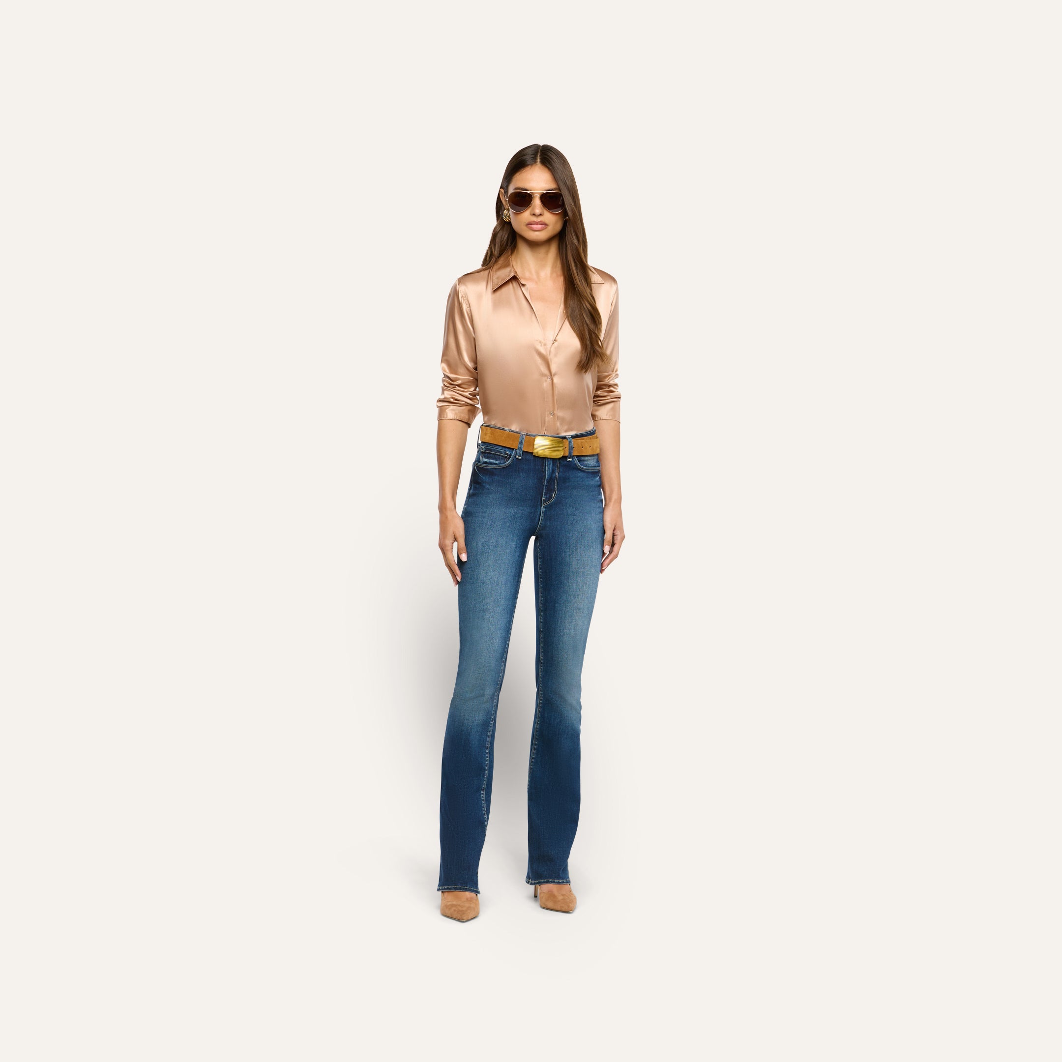 A person wearing a tan button-down shirt, blue flare jeans, a cognac brown Montell Suede Belt with a gold buckle, and sunglasses.