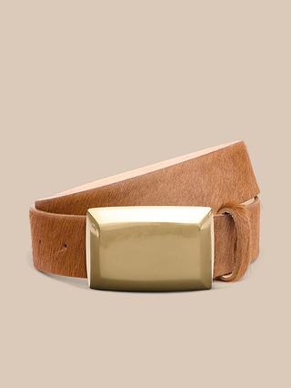 A tan leather belt with a rectangular, shiny gold buckle is coiled neatly against a beige background.