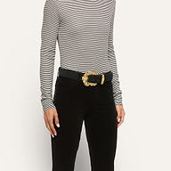 Caldera Suede Belt in black Italian calf suede with an ornate, gold-plated filigree buckle, worn over black pants and a striped long-sleeve shirt.