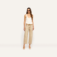 A woman in a white tank top and tan jeans wears a handcrafted Italian leather Bennett Leather Belt with a gold buckle.