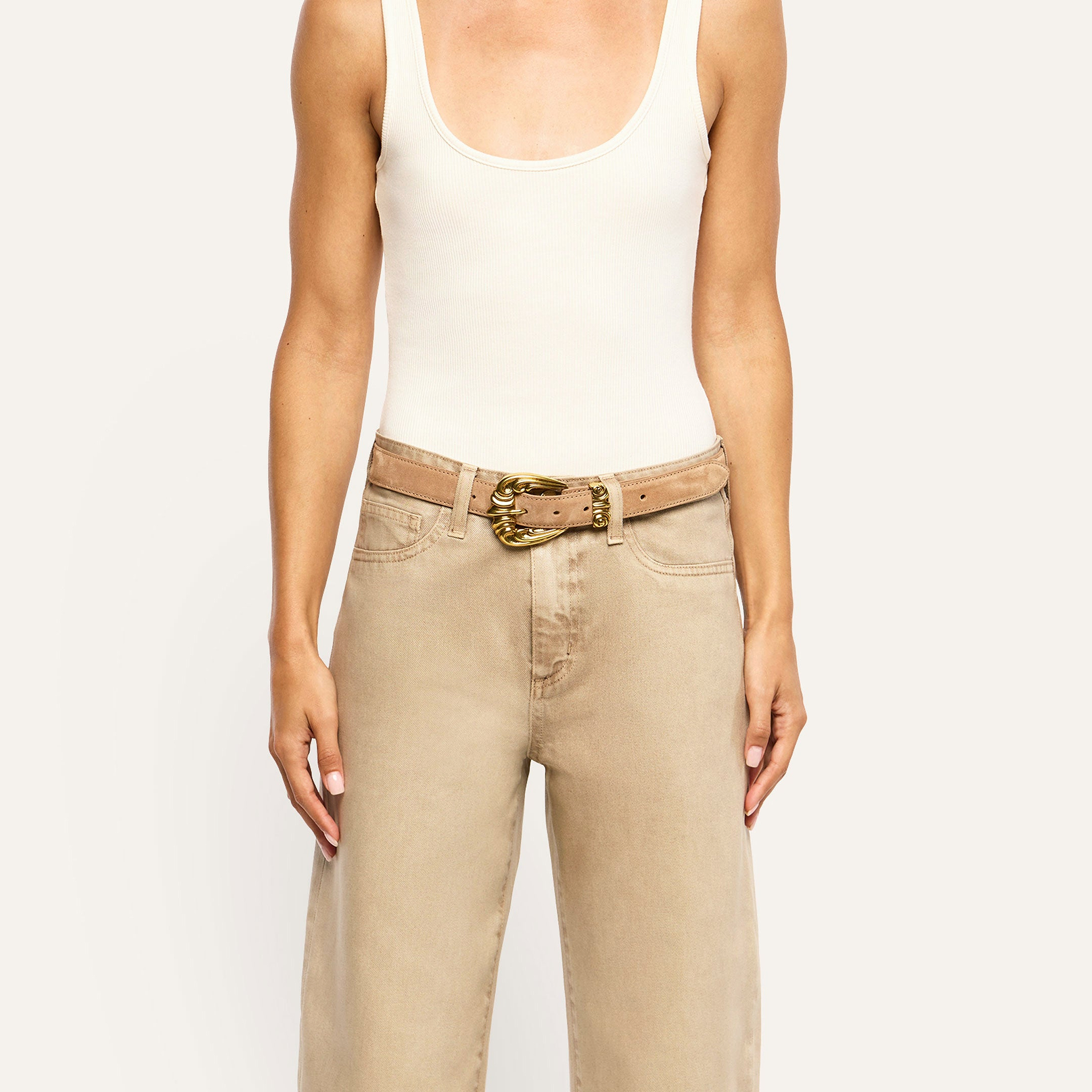 A tan Bennett Leather Belt with a gold-toned buckle worn with a white tank top and tan jeans.
