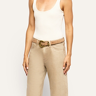 The Bennett Leather Belt, handcrafted in LA from tan Italian leather, features a decorative gold-tone metal buckle and is worn over tan jeans.